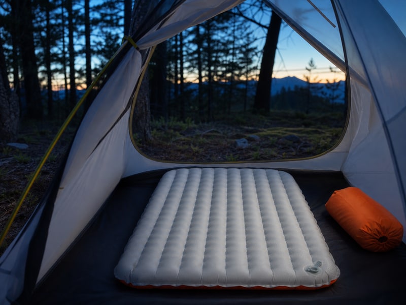 Tensor All-Seasonを想起させる橙色のアクセントを持つ登山用エアマットの使用イメージ